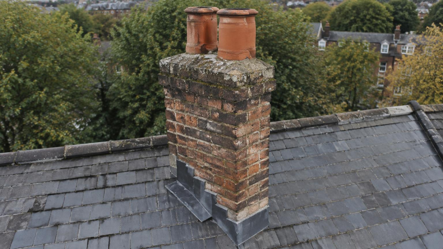 Close aerial view of a brick chimney stack with pots and lead flashing