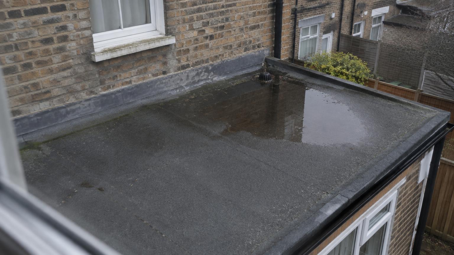 Felt flat roof on a rear extension with water ponding near the outlet